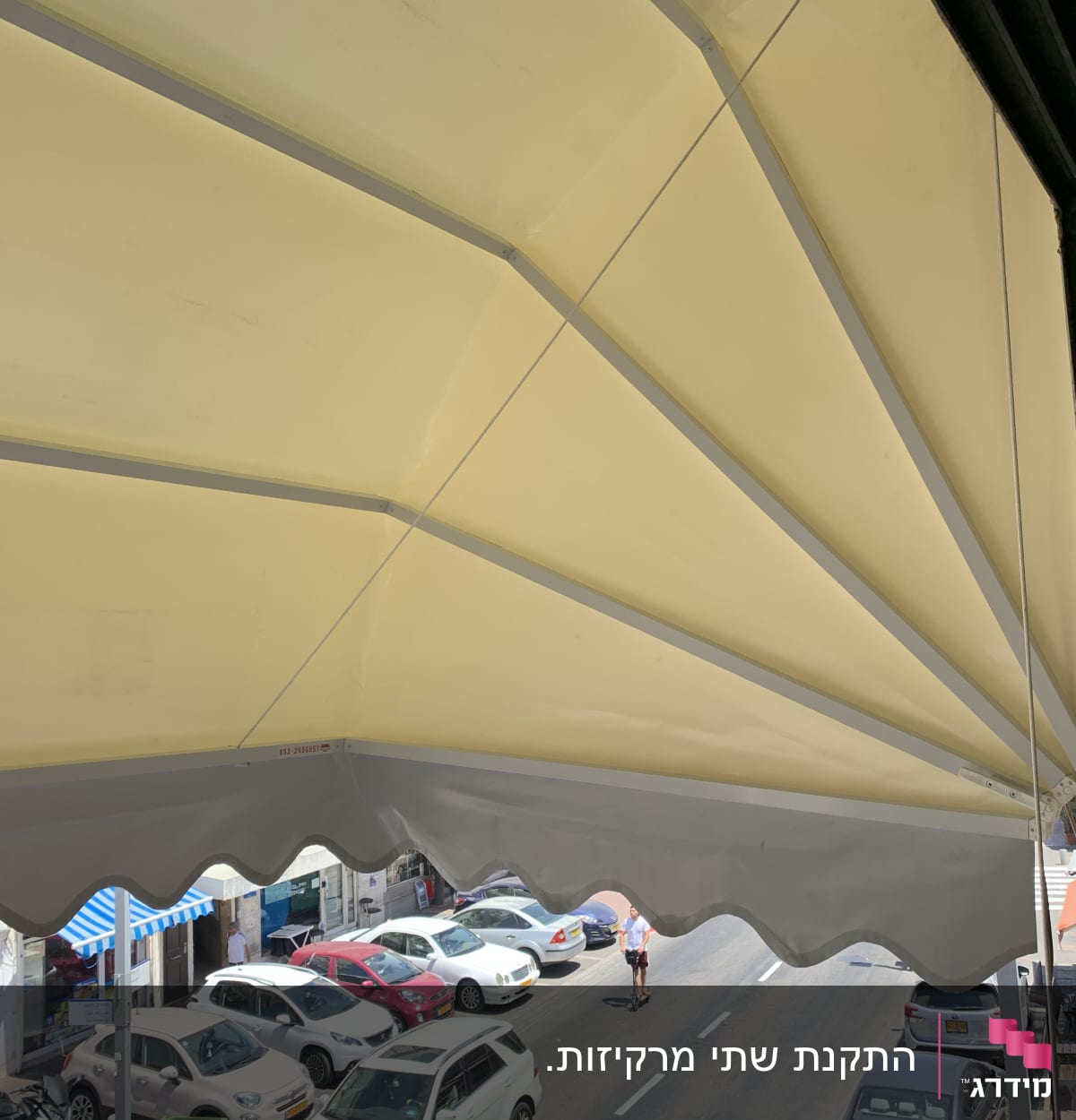 סוכך צהוב עם קצוות גליים מעל רחוב